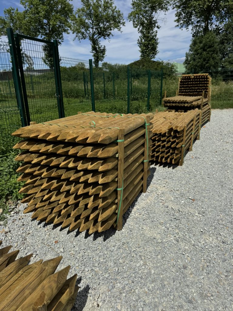 Piquets bois ronds traités autoclave classe 4 empilés au dépôt Structerra d’Épercieux-Saint-Paul