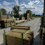 Piquets bois ronds traités autoclave classe 4 empilés au dépôt Structerra d'Épercieux-Saint-Paul